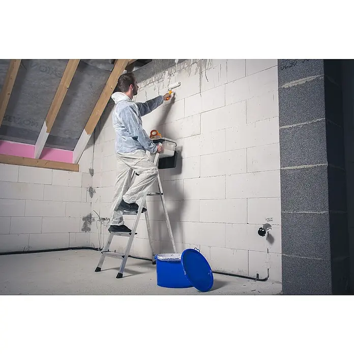 Krause Monto Stehleiter Secury MultiGrip - Anzahl Tritte: 4 Stk., Arbeitshöhe: 2,85 m, Belastbarkeit: 150 kg, Aluminium - Ein Mann auf einer Leiter streicht eine Wand mit einer Farbwalze, während ein blauer Farbbehälter am Boden steht.