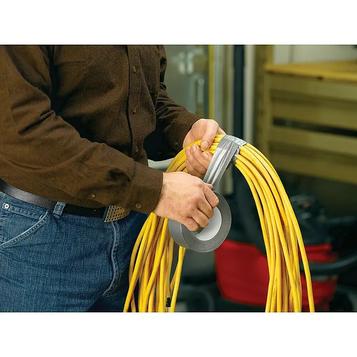 3M Cinta adhesiva universal Scotch americana - Gris, An x L: 48 mm x 25 m, 1 ud. - Una persona está asegurando un conjunto de cables de alimentación amarillos con cinta adhesiva gris para un almacenamiento ordenado.