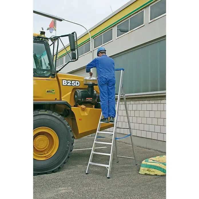 Krause Stabilo Stehleiter - Anzahl Tritte: 7 Stk., Arbeitshöhe: 3,65 m, Aluminium, Ablagefläche - Ein Mann in blauer Arbeitskleidung steht auf einer Krause Leiter vor einem gelben B25D Fahrzeug und arbeitet daran.