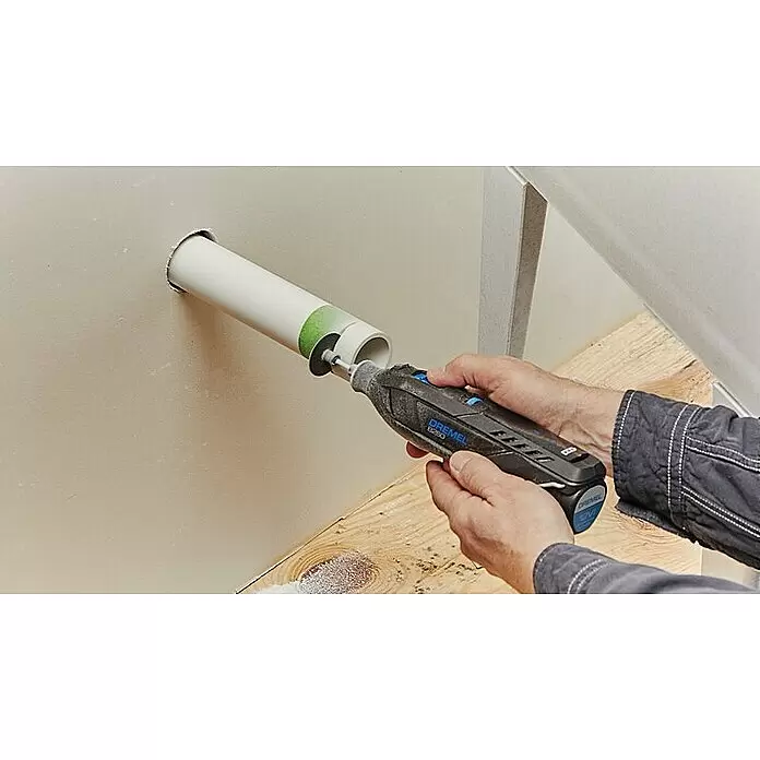 Dremel Akku-Rotationswerkzeug 8260-5 - 12 V, 1 Akku, 3 Ah, Leerlaufdrehzahl: 5.000 U/min - 30.000 U/min - Eine Person benutzt ein Dremel-Rotationswerkzeug mit Trennscheibe, um ein weißes PVC-Rohr an einer Wand zu kürzen.