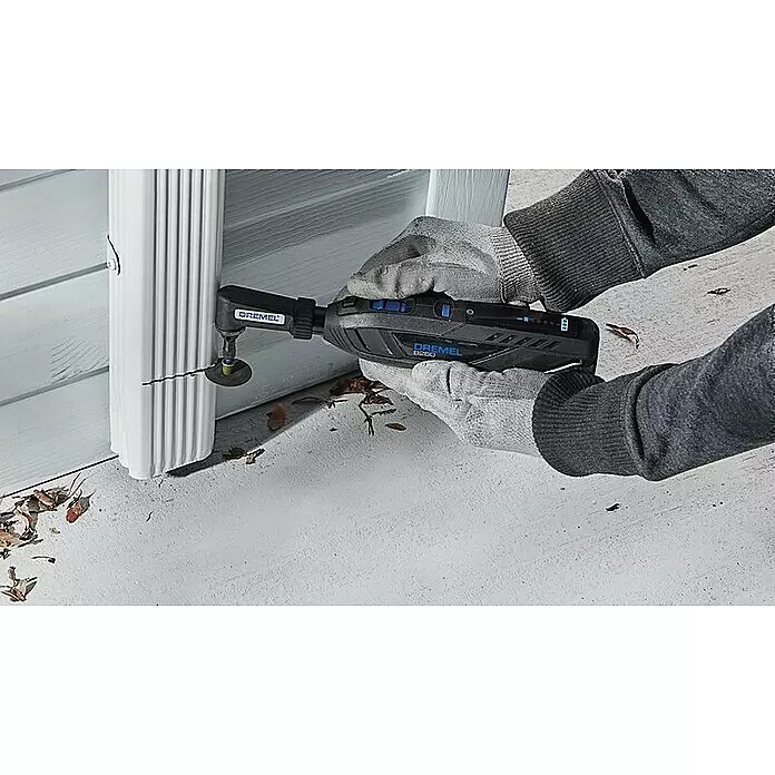 Dremel Akku-Rotationswerkzeug 8260-5 - 12 V, 1 Akku, 3 Ah, Leerlaufdrehzahl: 5.000 U/min - 30.000 U/min - Eine Person mit Handschuhen verwendet ein schwarzes Dremel Akku-Multifunktionswerkzeug mit einem Winkelvorsatz zum Schneiden eines weißen Fallrohrs.