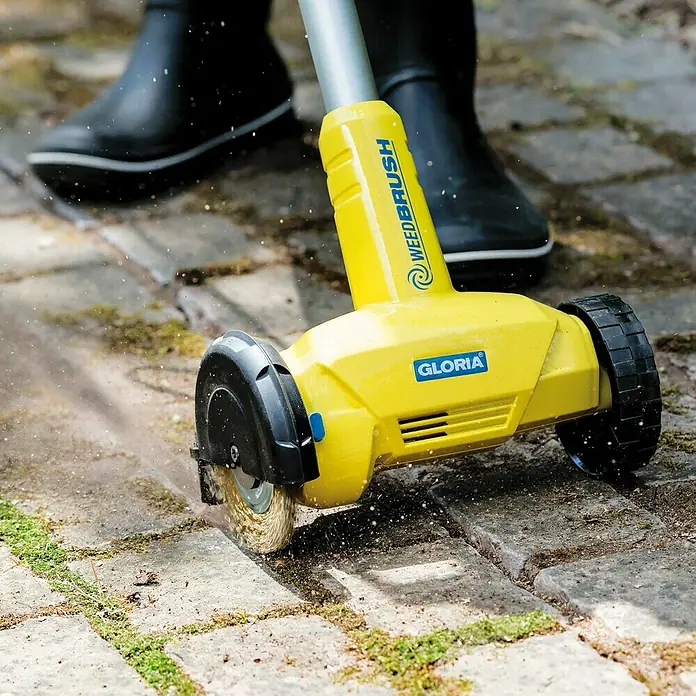 Gloria WeedBrush Fugenreiniger300 W, 1.800 U/min - Der Gloria WeedBrush in Aktion, um Unkraut zwischen Pflastersteinen zu entfernen. Effektive und umweltfreundliche Gartenpflege.