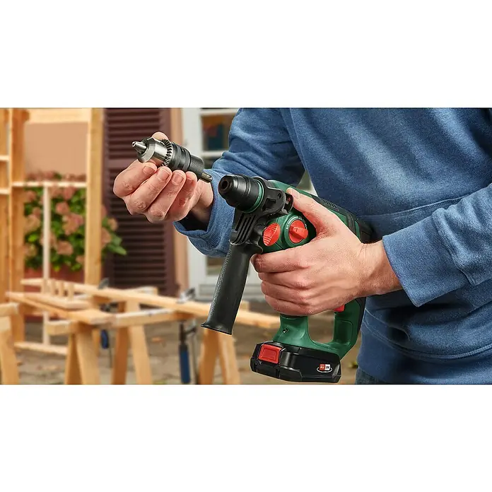 Bosch Power for All 18V Akku-Kombihammer UniversalHammer 18V - 18 V, Ohne Akku, 2 J - Nahaufnahme einer Person, die eine grüne Bosch-Bohrmaschine mit austauschbarem Bohrfutter in der Hand hält, bereit für den Einsatz bei Bauprojekten.