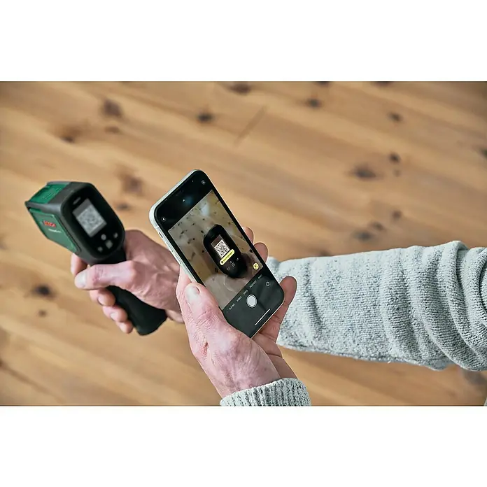 Bosch Advanced Temperaturmessgerät AdvancedTemp - Messbereich: -30 °C bis +500 °C - Eine Person fotografiert mit einem Smartphone einen Bosch-Wärmemelder, um seine QR-Code-Informationen zu erfassen.