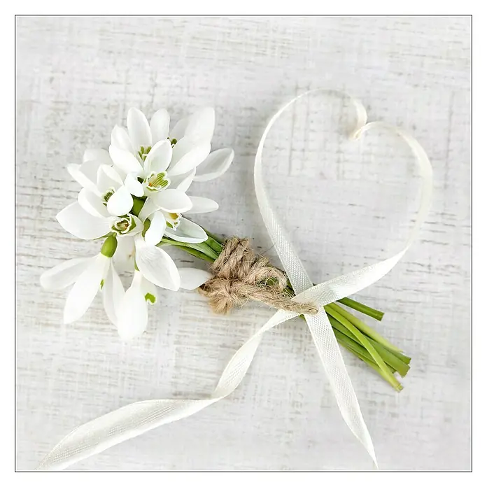 Glasbild - White Spring I, B x H: 20 x 20 cm - Ein zarter Strauß Schneeglöckchen, gebunden mit rustikalem Zwirn und einem weißen Band, das in Herzform drapiert ist.