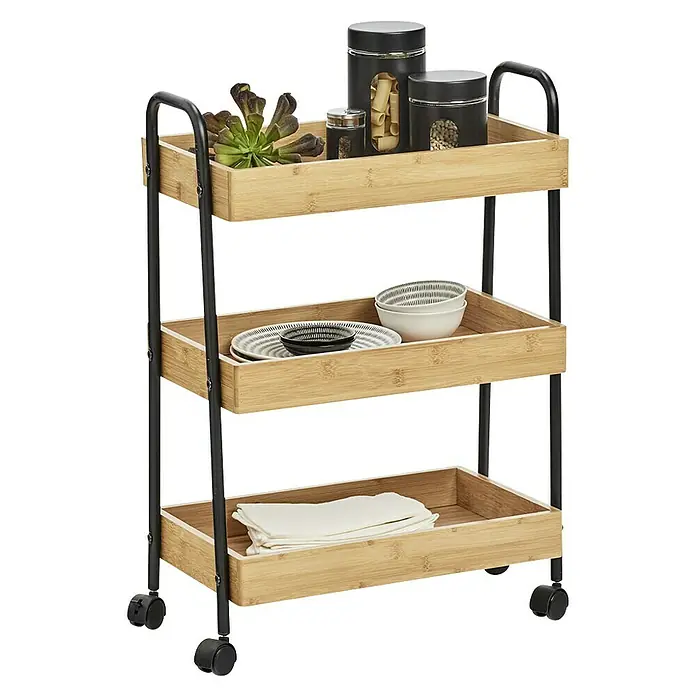 Zeller Present Carro con ruedas bambú - 28 x 50 x 70 cm, Bambú - Imagen de un carrito de cocina de bambú de tres niveles, lleno de botes, platos y servilletas, sobre un fondo negro.