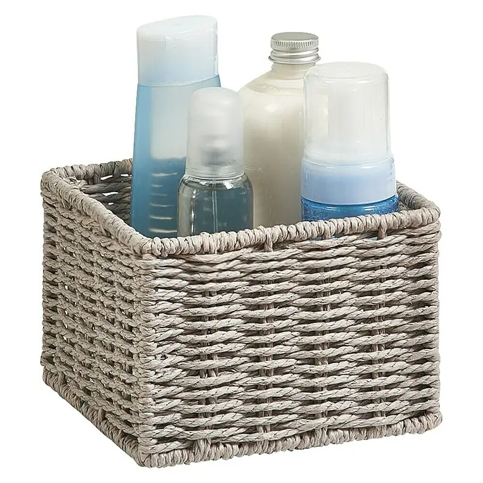 Zeller Present Juego de cestas Conjunto de 2 cestas para el baño - Gris, 2 pzs. - La imagen muestra una cesta de almacenamiento tejida llena de artículos de tocador surtidos. La cesta está hecha de un material ligero de color neutro.