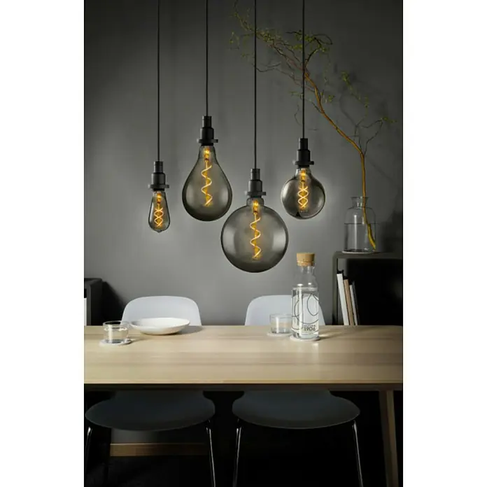 Osram Vintage 1906 Bombilla LED - E27, Blanco cálido, 150 lm, 5 W - Elegantes lámparas colgantes de diferentes formas sobre una mesa de comedor, creando un ambiente cálido y acogedor.