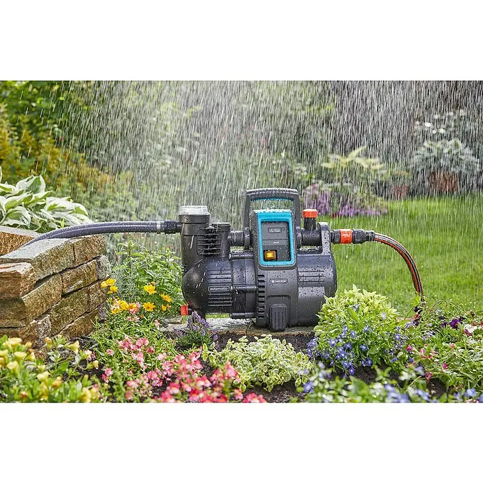 Gardena Bewässerungspumpe Haus- & Gartenautomat 4000/5 - 1.100 W, Max. Fördermenge: 4.000 l/h - Bild einer Gardena Gartenpumpe, die im Garten unter Regenschauern steht und Blumen bewässert.