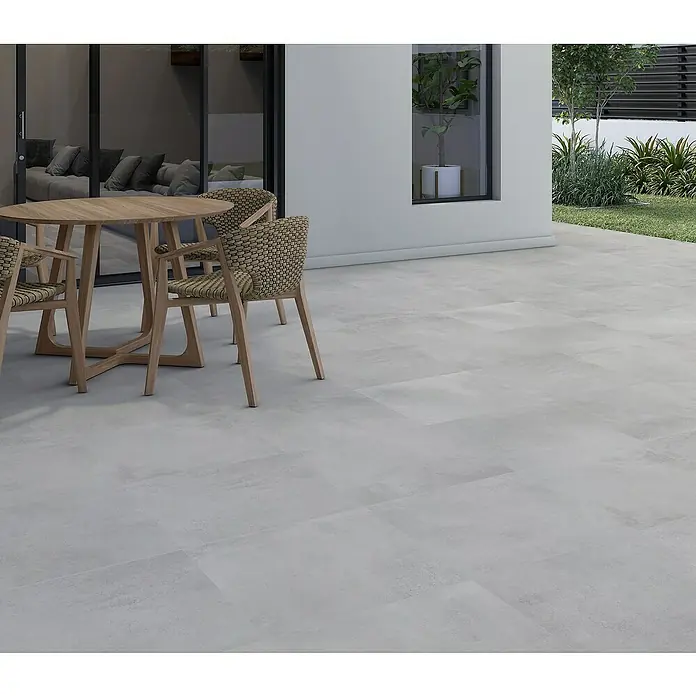 Pavimento porcelánico Madox - 33,3 x 33,3 cm, Gris, Mate - Foto exterior que muestra elegantes baldosas de patio de color gris claro, que complementan perfectamente una zona de estar moderna con mesa y sillas.