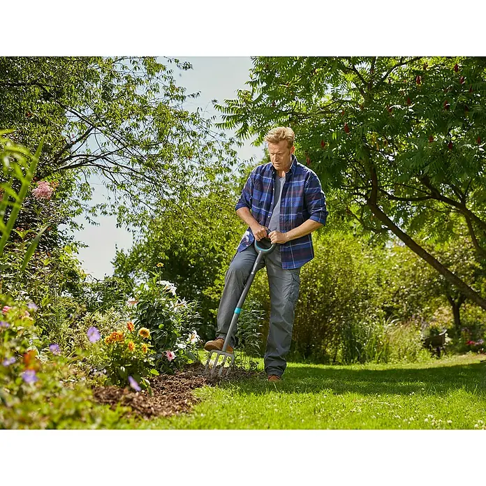Gardena Ergoline Spatengabel - Anzahl Zinken: 4, Ergonomischer Stiel - Mann arbeitet im Garten mit einem Gardena-Spaten, um den Boden vorzubereiten. Ideal für Gartenarbeit und Landschaftsbau.