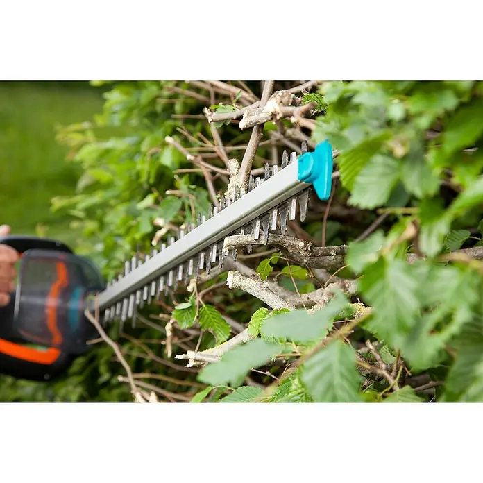 Gardena PowerCut Elektro-Heckenschere 700/65 - 700 W, Schnittlänge: 65 cm - Eine Heckenschere schneidet Äste und Blätter. Die Klinge ist silbern und der Griff ist schwarz mit orangen Akzenten.