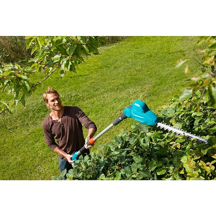 Gardena Teleskop-Heckenschere THS 500/48 - 500 W, Schwertlänge: 48 cm - Ein Mann bedient einen Gardena Akku-Hochentaster, um eine Hecke zu schneiden, mit Fokus auf das Gartengerät.
