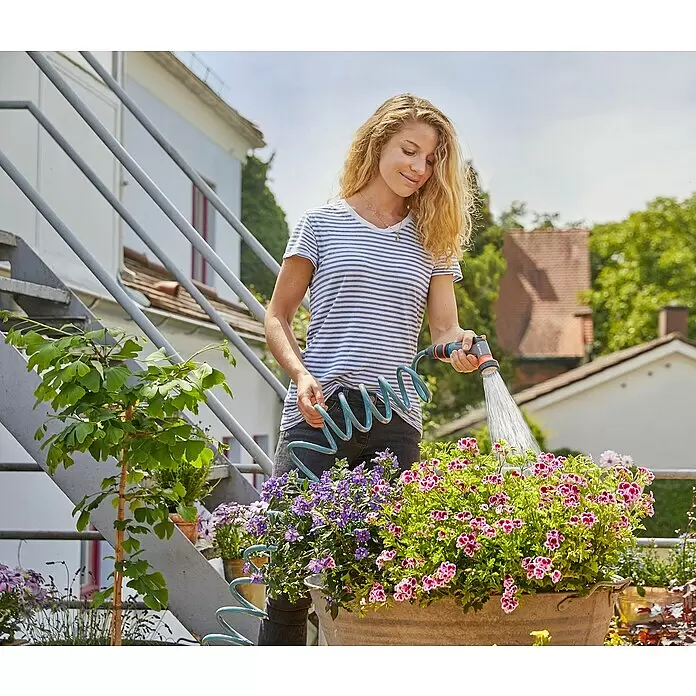 Gardena City Gardening Bewässerungsbrause - Anzahl Sprühformen: 1 Stk., Kunststoff - Eine Frau bewässert bunte Blumen in einem großen Topf auf einer Terrasse mit einem blauen Spiralschlauch und einer grau-orangen Brause.
