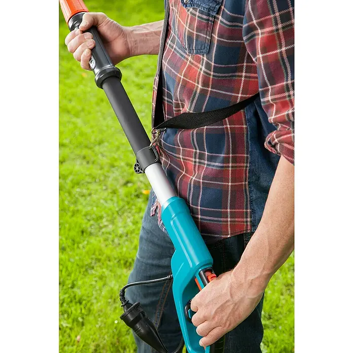 Gardena Elektro-Hochentaster TCS 720/20 - Teleskopstiel - Nahaufnahme einer Person, die eine elektrische Gartenschere mit einem Tragegurt hält, ideal für präzise Baumpflege.