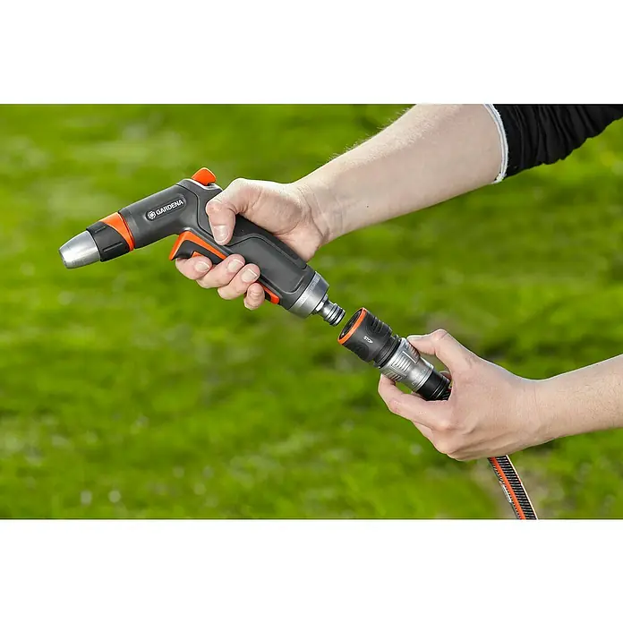 Gardena Premium Pistola de riego con conectores - 2 pzs., Plástico - Una boquilla de rociador de jardín Gardena que se está uniendo a un conector de manguera, sostenida por dos manos, sobre un césped verde.