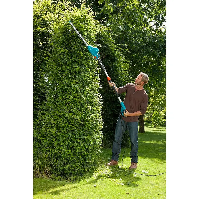 Gardena Teleskop-Heckenschere THS 500/48 - 500 W, Schwertlänge: 48 cm - Mann schneidet eine hohe Hecke mit einer Gardena Akku-Teleskop-Heckenschere.