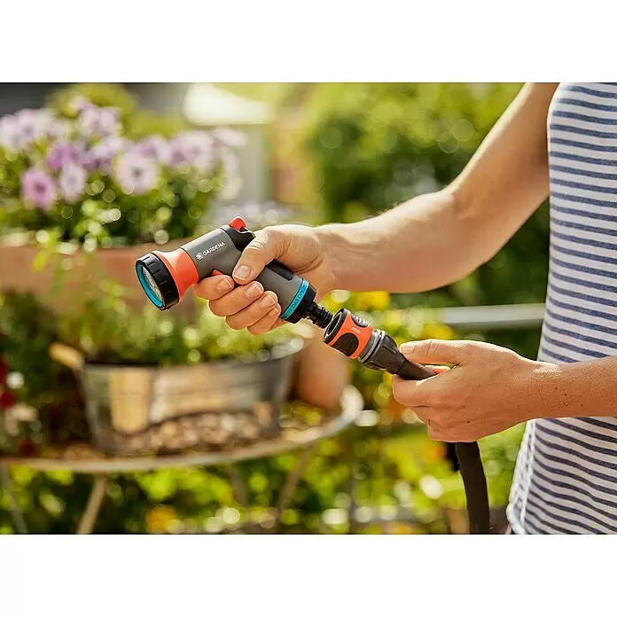 Gardena City Gardening Bewässerungsbrause - Anzahl Sprühformen: 1 Stk., Kunststoff - Eine Hand hält eine grau-orange Gardena Brause und verbindet sie mit einem schwarzen Schlauch.