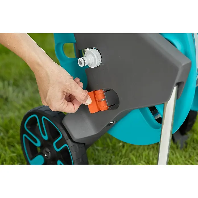Gardena Schlauchwagen CleverRoll M - Kunststoff/Metall, Schlauchkapazität: 60 m, 13 mm (½″) - Nahaufnahme des Gardena AquaRoll M Gartenschlauchwagens mit einer Hand, die eine orangefarbene Klappe bedient.