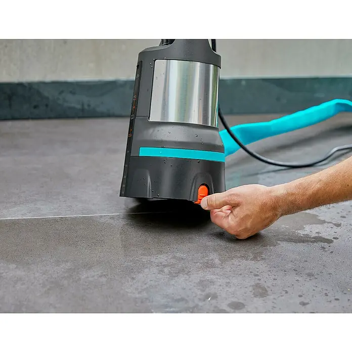 Gardena Klarwasser-Tauchpumpe 11000 Aquasensor - 450 W, Max. Fördermenge: 11.000 l/h - Nahaufnahme einer Gardena Schmutzwasser-Tauchpumpe beim Betätigen des Einschalters auf einem gefliesten Boden.