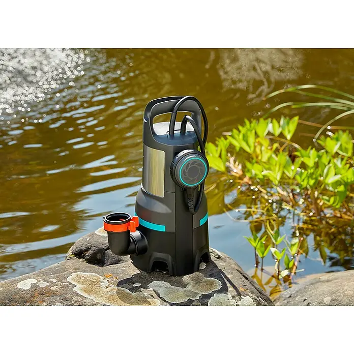 Gardena Schmutzwasserpumpe 25000 - 1.100 W, Max. Fördermenge: 25.000 l/h, Eintauchtiefe: 7 m - Eine Gardena Schmutzwasserpumpe auf einem Stein neben einem Teich, ideal für Gartenarbeiten und Entwässerung.