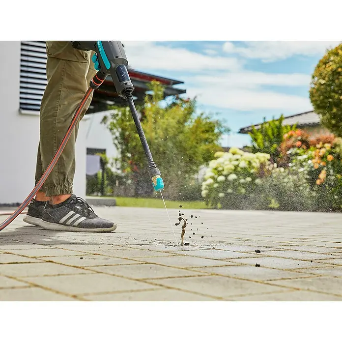 Gardena Power for All 18V Akku-Druckreiniger AquaClean 24/18V SE - 18 V, 1 Akku, 2,5 Ah - Eine Person benutzt einen Gardena-Hochdruckreiniger, um einen Gehweg zu reinigen. Das Gerät entfernt mühelos Schmutz und Ablagerungen.