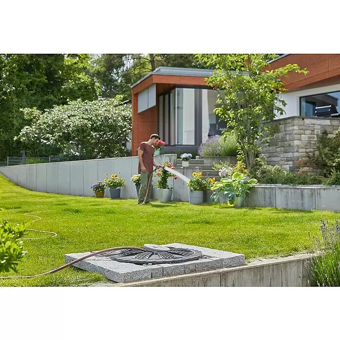 Gardena Tauchpumpe 5900/4 INOX Automatic - 900 W, Max. Fördermenge: 5.900 l/h - Dunkelgraues, rundes Schlauchführungssystem, durch das ein roter Gartenschlauch läuft, in einen hellgrauen Steinblock eingesetzt.