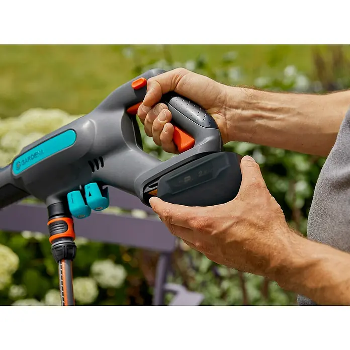 Gardena Power for All 18V Akku-Druckreiniger AquaClean 24/18V SE - 18 V, 1 Akku, 2,5 Ah - Nahaufnahme einer Person, die eine Gardena Akku-Spritzpistole mit auswechselbarem Akku hält, ideal für die Gartenbewässerung.