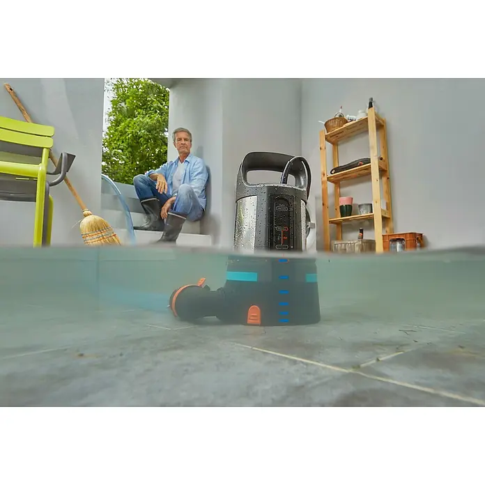 Gardena Klarwasser-Tauchpumpe 11000 Aquasensor - 450 W, Max. Fördermenge: 11.000 l/h - Das Bild zeigt eine Gardena-Pumpe, die im Wasser steht. Sie ist schwarz und blau, mit einem grauen Gehäuse. Eine Person sitzt im Hintergrund.