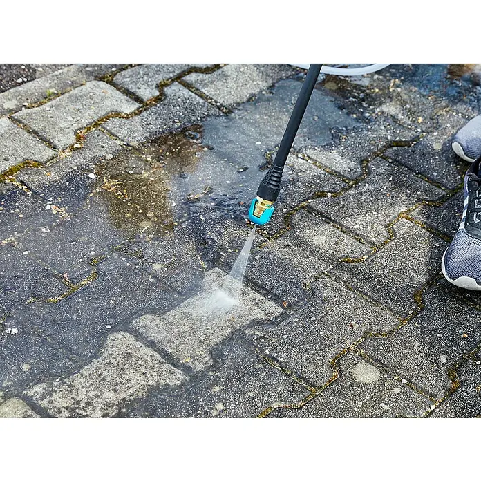 Gardena Power for All 18V Akku-Druckreiniger AquaClean 24/18V SE - 18 V, 1 Akku, 2,5 Ah - Ein Hochdruckreiniger wird verwendet, um einen gepflasterten Bereich zu reinigen. Die Steine werden durch den Wasserstrahl sauberer.
