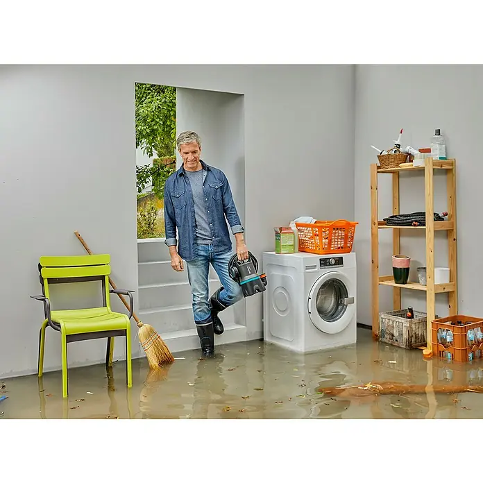Gardena Schmutzwasserpumpe 9000 - 300 W, Max. Fördermenge: 9.000 l/h, Eintauchtiefe: 7 m - Mann mit Gardena Schmutzwasser-Tauchpumpe im überfluteten Raum, bereit zum Abpumpen des Wassers. Praktische Lösung für Notfälle.