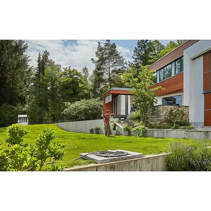 Gardena Tauchpumpe 5900/4 INOX Automatic - 900 W, Max. Fördermenge: 5.900 l/h - Ein Mann bewässert Topfpflanzen mit einem Gartenschlauch, der an ein bodenbündiges Rollsystem angeschlossen ist.