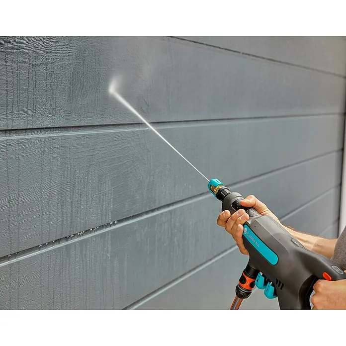 Gardena Power for All 18V Akku-Druckreiniger AquaClean 24/18V SE - 18 V, 1 Akku, 2,5 Ah - Hochdruckreiniger in Aktion: Eine Gardena-Pistole reinigt eine graue Wand mit einem starken Wasserstrahl und entfernt Schmutz.