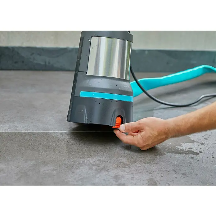 Gardena Klarwasser-Tauchpumpe 11000 Aquasensor - 450 W, Max. Fördermenge: 11.000 l/h - Nahaufnahme einer Person, die eine Gardena-Gartenpumpe auf einem grauen Fliesenboden bedient.