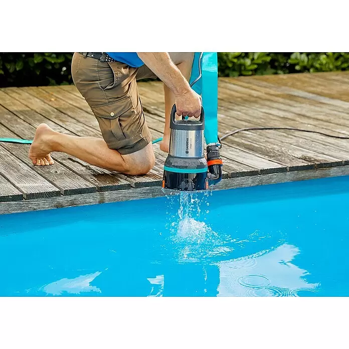 Gardena Klarwasser-Tauchpumpe 17000 Aquasensor - 750 W, Max. Fördermenge: 17.000 l/h - Person nutzt eine silberne Gardena Tauchpumpe mit türkisen Akzenten, um Wasser aus einem Pool abzupumpen.