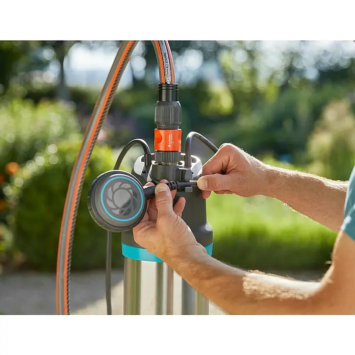 Gardena Drucktauchpumpe 5900/4 Inox - 900 W, Max. Fördermenge: 5.900 l/h - Nahaufnahme einer Gardena-Tauchdruckpumpe, die von Händen bedient wird, um sie einzustellen. Ideal für Gartenbewässerung und Entwässerung.