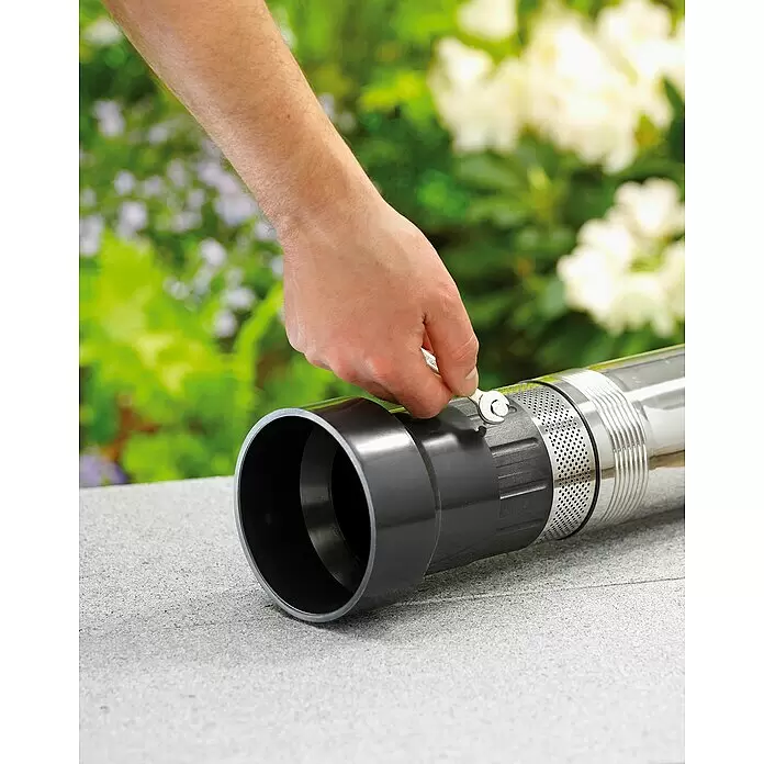 Gardena Tiefbrunnenpumpe 6000/5 Inox automatic - 950 W, Max. Fördermenge: 6.000 l/h, Max. Druck: 5 bar - Hand zieht eine Schelle an einem schwarzen PVC-Rohr an, das mit einer silbernen Tauchpumpe verbunden ist.