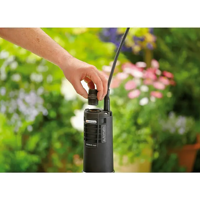 Gardena Tiefbrunnenpumpe 6000/5 Inox automatic - 950 W, Max. Fördermenge: 6.000 l/h, Max. Druck: 5 bar - Nahaufnahme einer Gardena-Gartenpumpe, bei der ein Anschlussstück montiert wird, ideal für die Bewässerung.