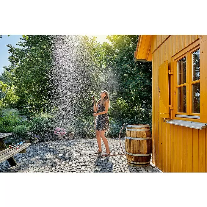 Gardena Regenfasspumpe 4000/1 - 400 W, Max. Fördermenge: 4.000 l/h - Frau bewässert Pflanzen im Garten mit einem Schlauch und einer Sprühdüse.