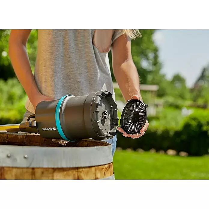 Gardena Regenfasspumpe 4000/1 - 400 W, Max. Fördermenge: 4.000 l/h - Person hält eine schwarze Gardena Tauchpumpe mit blauem Band. Der abnehmbare Filterdeckel mit weißem Netz wird separat gehalten.