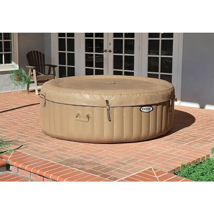 Intex Pure Spa Hidromasaje móvil Bubble - Ø x Al: 196 x 71 cm, Beige/Blanco, 800 l - Un jacuzzi Intex se encuentra al aire libre, cubierto y listo para relajarse en un patio de ladrillo.