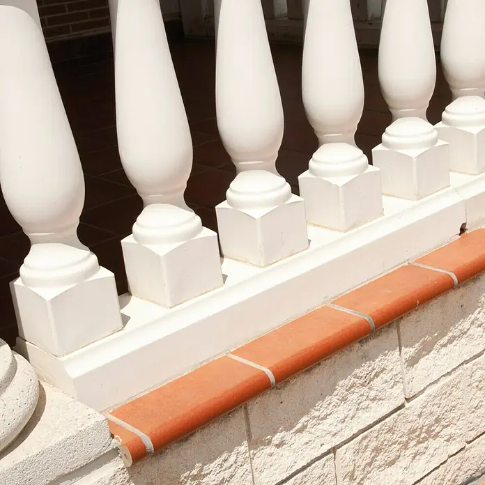 Pasamano Roma - Hormigón - Detalle de una balaustrada blanca con detalles de ladrillo rojo en una terraza, destacando elementos arquitectónicos y texturas.