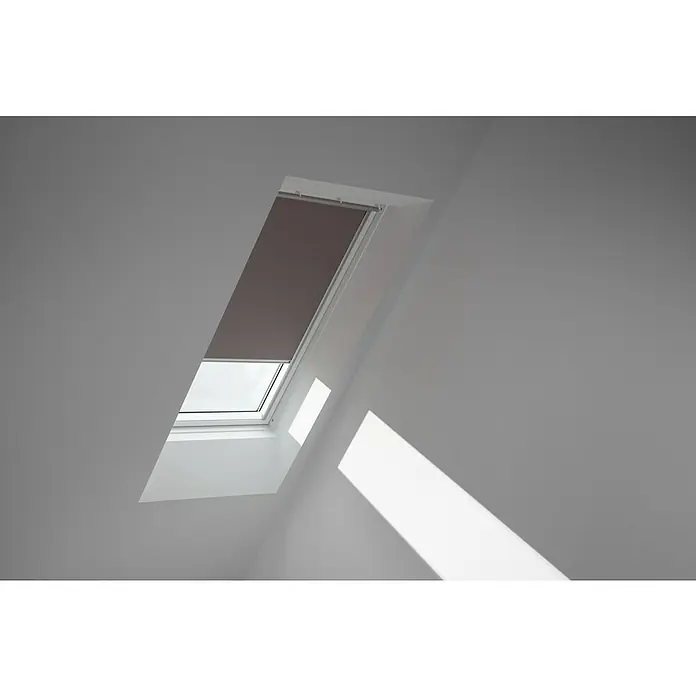 Velux Dachfensterrollo DKL SK08 4577S - Farbe: Taupe - 4577S, Farbe Schiene: Aluminium, Manuell - Das Bild zeigt ein Dachfenster mit einem Rollo, das teilweise heruntergezogen ist und Licht in den Raum lässt. Das Fenster ist in eine schräge Decke eingelassen.