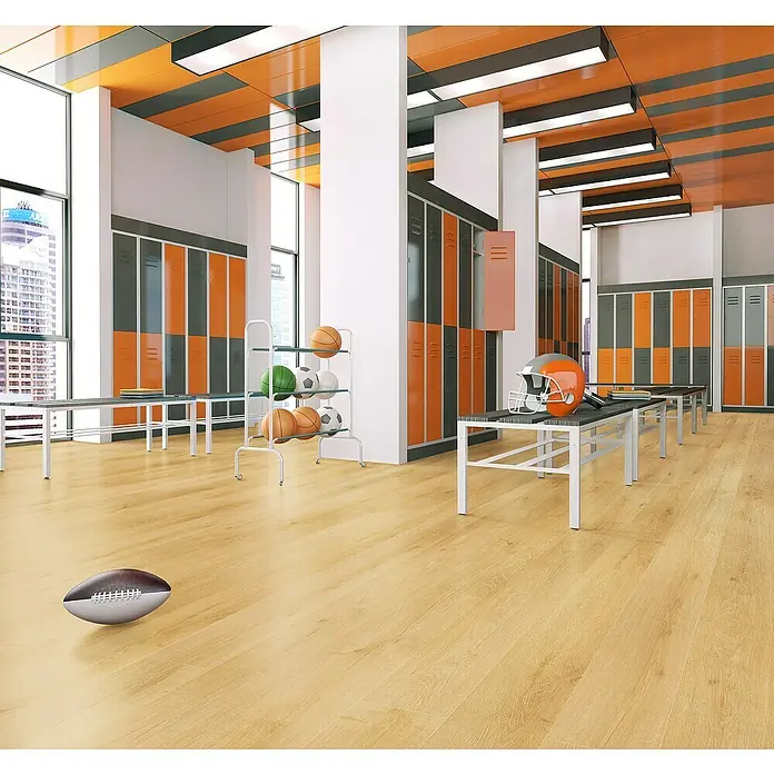LOGOCLIC Junta de transición Maui - 2,44 m x 42 mm x 16 mm, Pegado - Vista interior de un vestuario con taquillas, bancos, equipamiento deportivo y un balón de fútbol en el suelo. El suelo de madera clara complementa la paleta.