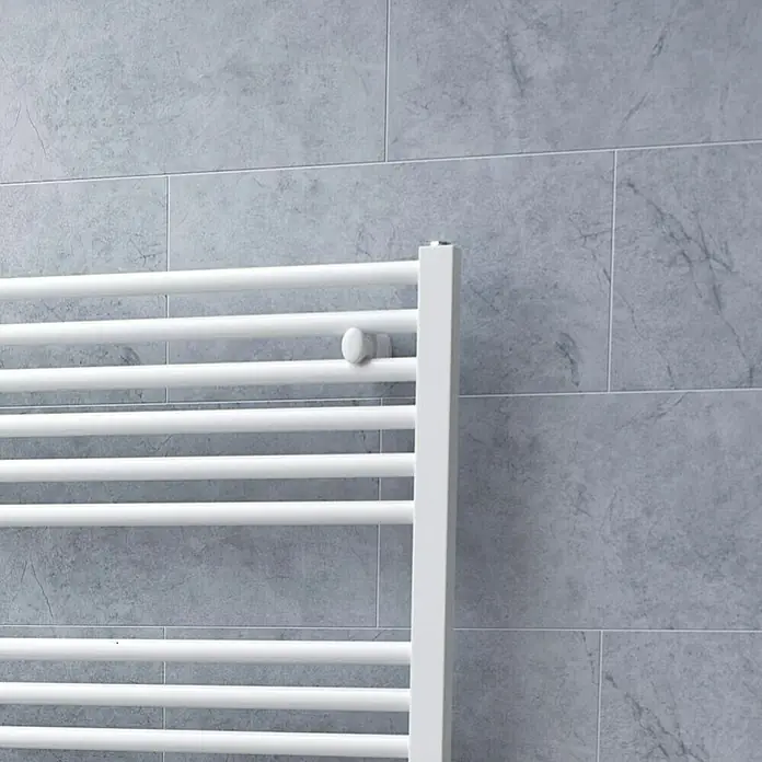 Ximax Badheizkörper Centrino - B x H: 600 x 1.120 mm, Wärmeleistung bei Vorlauftemperatur von 75 °C (D: 50): 620 W - Detailaufnahme eines weißen Handtuchwärmers vor einer grauen Fliesenwand. Das minimalistische Design des Heizkörpers betont die moderne Badezimmerästhetik.