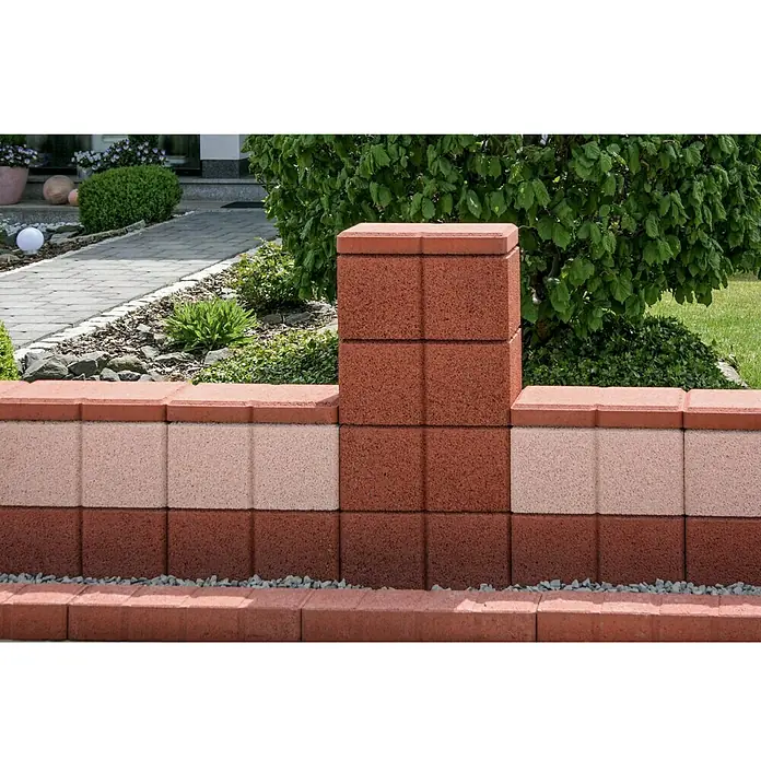 Christoph Gartenmauer Ambienta - 40 x 20 x 20 cm, Mediterran, Beton - Mauer mit rotbraunen und hellrosa Steinen im Garten. Die Mauer dient als dekoratives Element und Grundstücksbegrenzung.