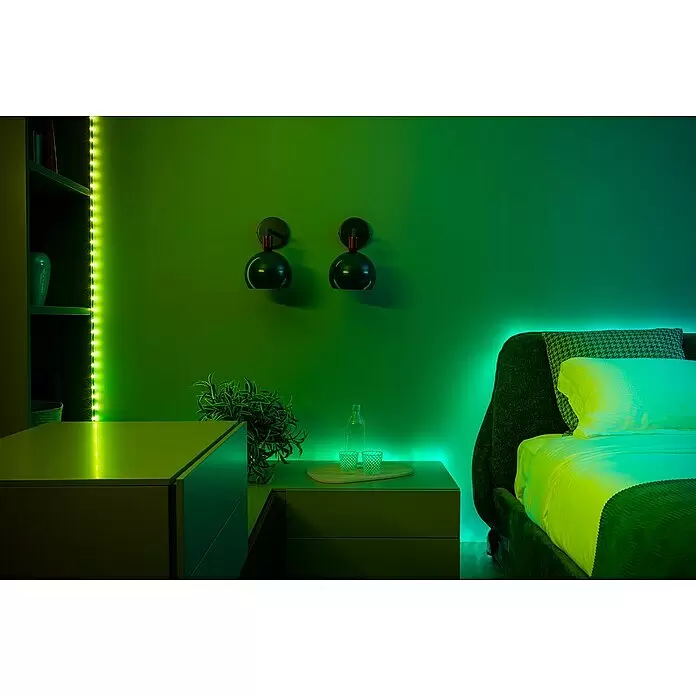 Twinkly Smart-LED-Band Dots - Länge: 10 m, RGB, 24 W, Schwarz - Schlafzimmer mit grüner LED-Streifenbeleuchtung entlang von Regalen und hinter dem Bett, die ein stimmungsvolles Licht erzeugt.