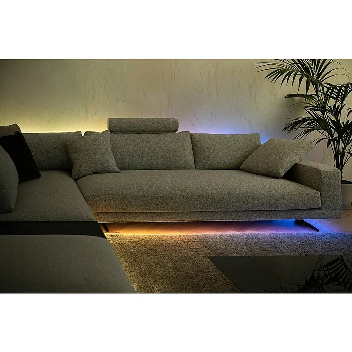 Twinkly Tira de luces LED Flex - Largo: 2 m, Color de luz: RGB, 15 W - Un moderno sofá modular gris con iluminación ambiental LED que crea un ambiente cálido y acogedor en la habitación.