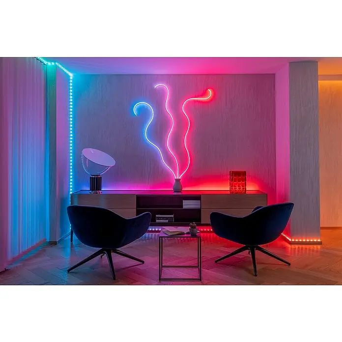 Twinkly Tira de luces LED Flex - Largo: 2 m, Color de luz: RGB, 15 W - Una sala de estar con iluminación LED que crea un ambiente acogedor, con luces de cambio de color y muebles elegantes.