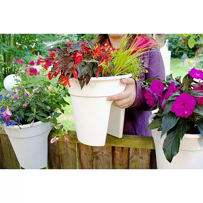 KHW Geländertopf Flowerclip - Außenmaß (Ø x H): 27 x 27,5 cm, Kunststoff, Weiß - Weißer Geländer-Pflanzkübel mit Pflanzen, von einer Person gehalten und auf einem Holzzaun befestigt.